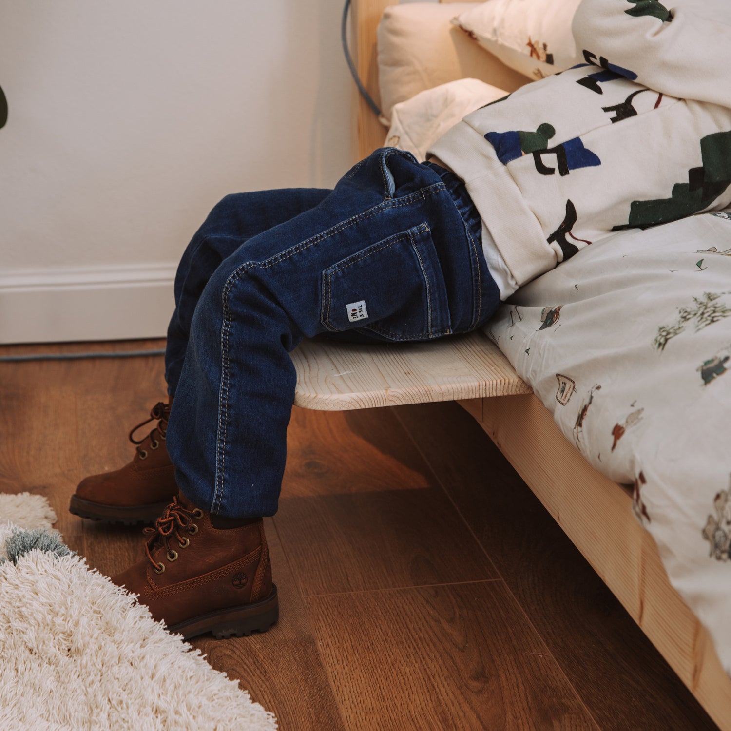 bambino seduto su comodino per letto montessoriano in legno massello