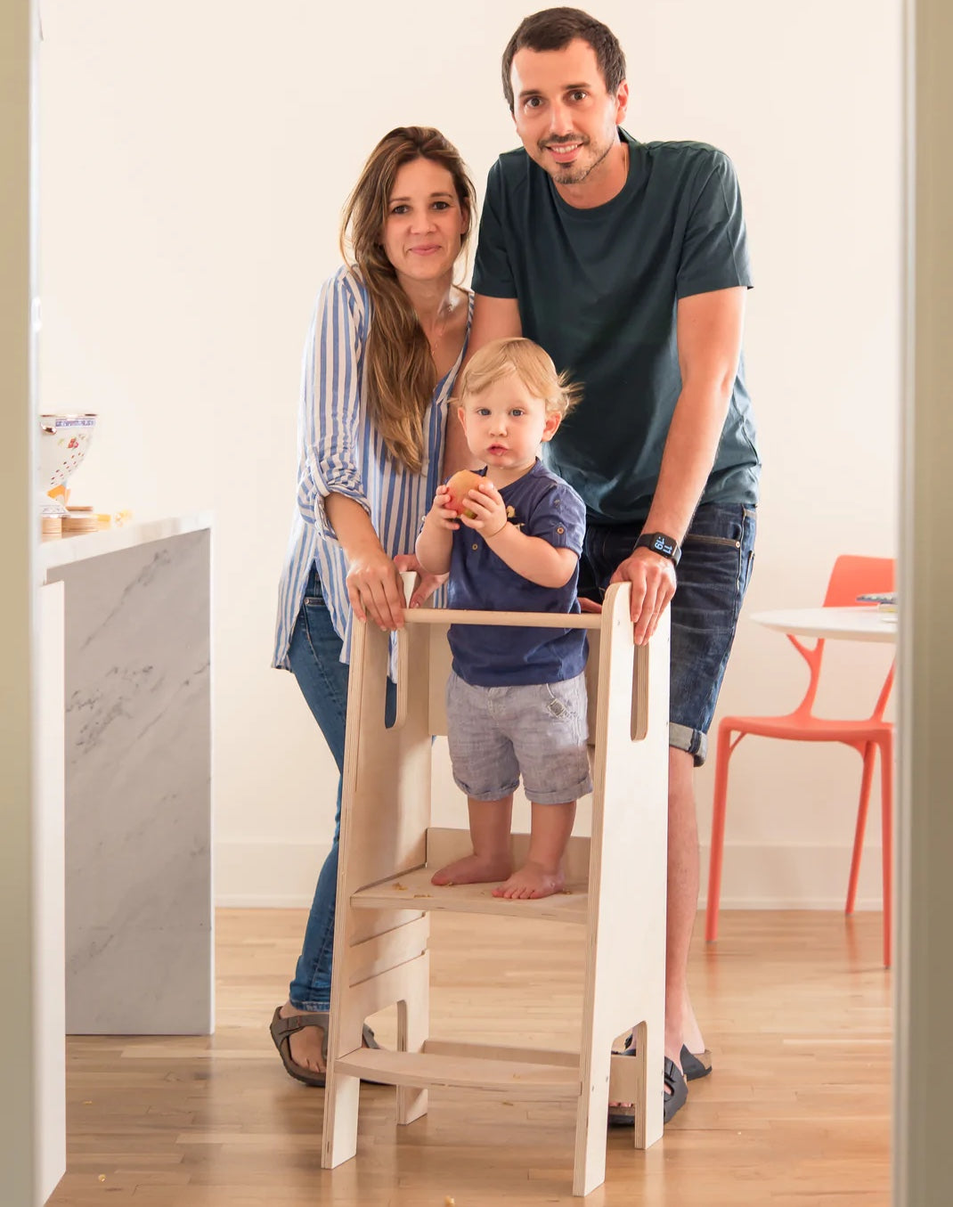 genitori vicino a bambino piccolo in piedi su torre di apprendimento montessori