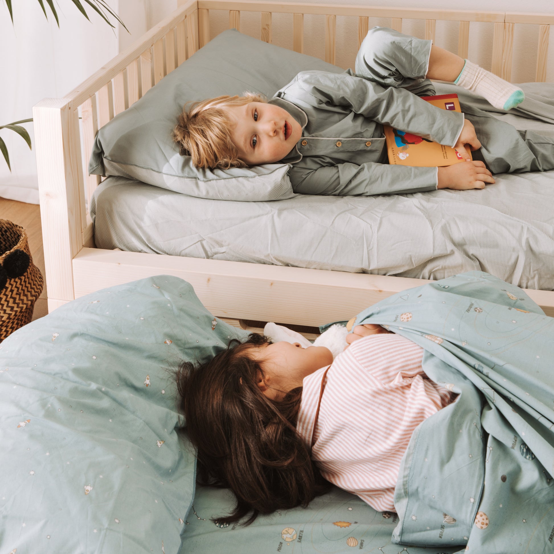 due bambini distesi su letto montessoriano zero+ con cassettone e secondo letto estraibile 